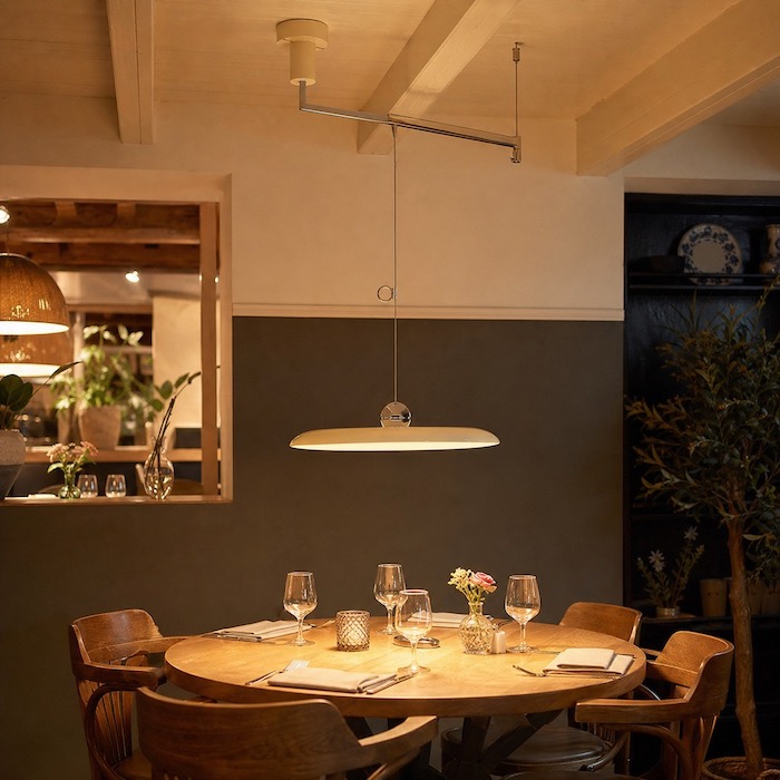 Adjustable swing arm pendant moving light over a dining table.