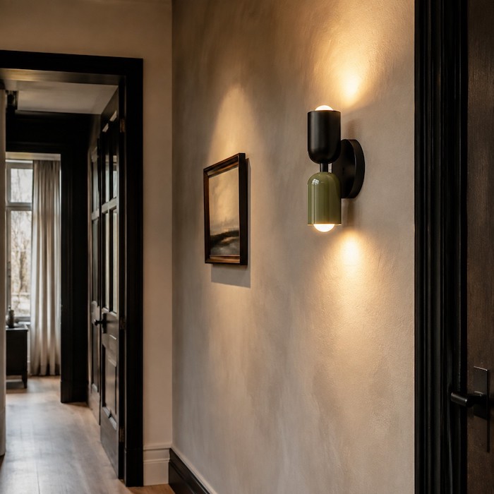 Warm sconce light revealing subtle plaster texture in a residential hallway.