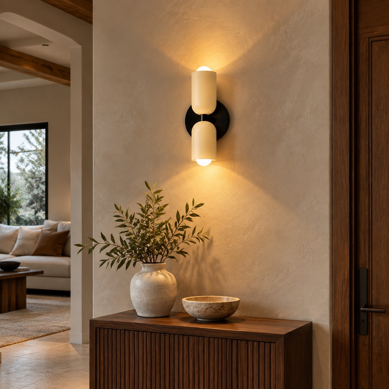 Warm wall light grazing a limewashed entry wall above a narrow cabinet.