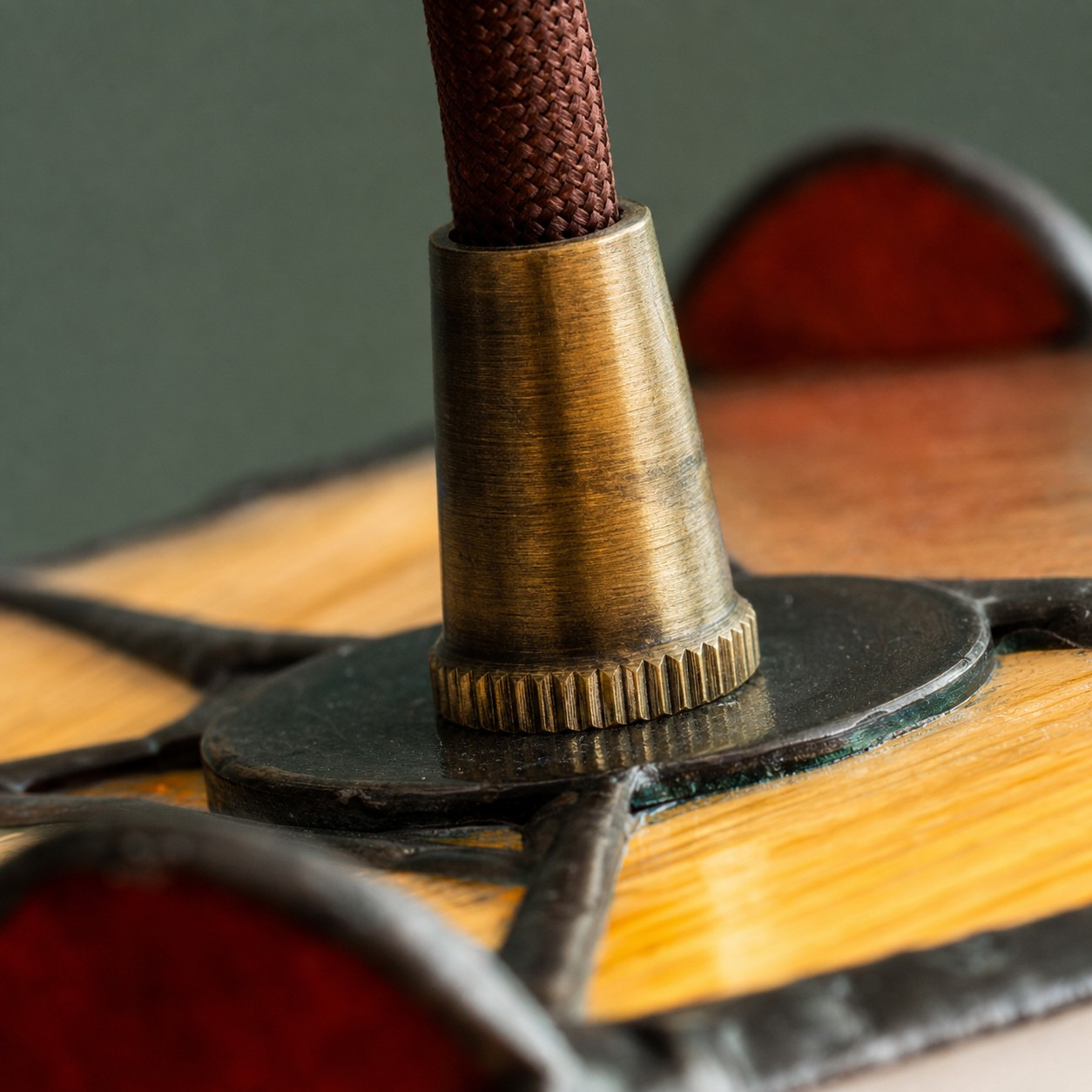 Brass-tone fitting and fabric-covered suspension cord close detail
