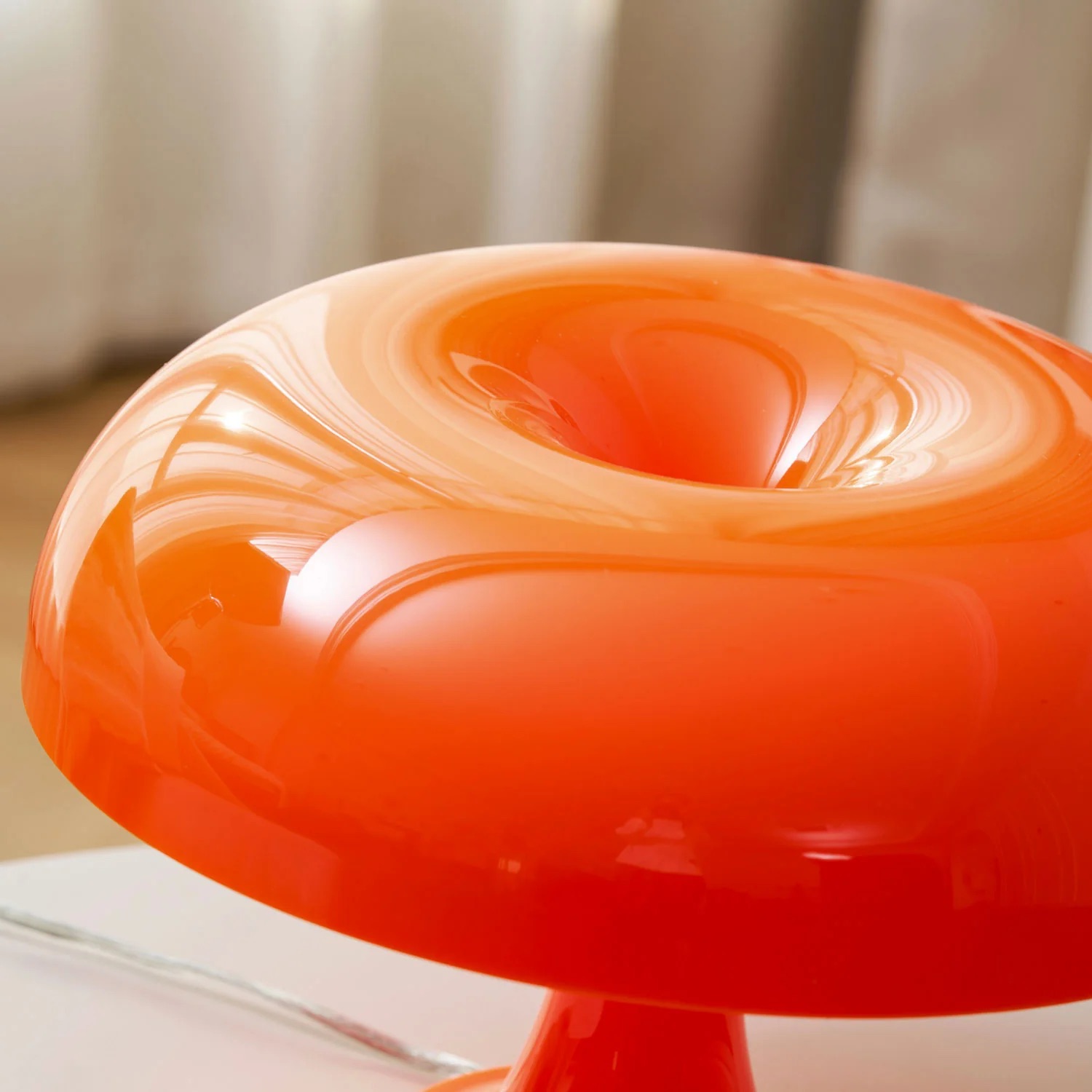 Close view of the glossy orange rounded shade and top opening